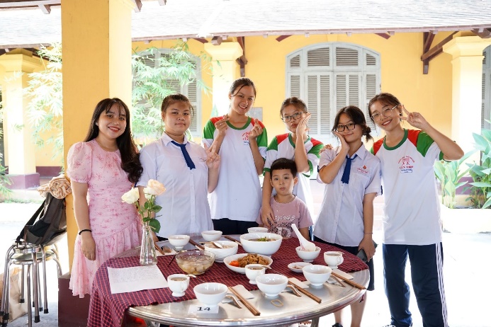 A group of people standing around a table with food

Description automatically generated